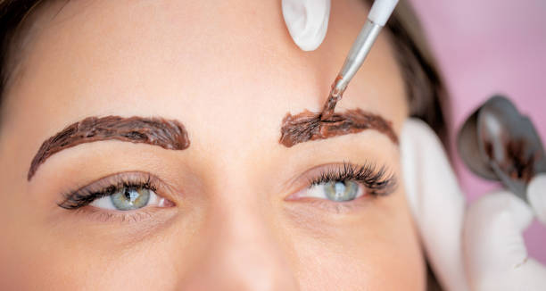 Close-up Photo of Beautician Dyeing Woman's Eyebrows - stock photo stock photo