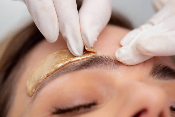 beautician extracción de pelos de cejas con cera - foto de stock - wax fotografías e imágenes de stock