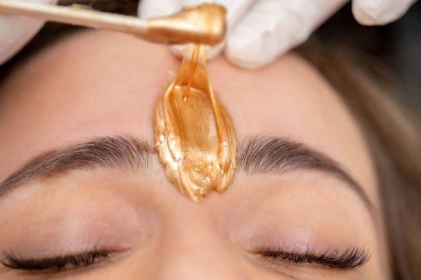 Applying Facial Wax Between Eyebrows - stock photo Applying Facial Wax Between Eyebrows wax stock pictures, royalty-free photos & images