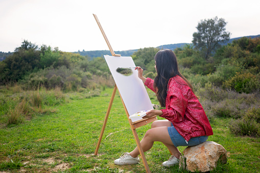 Young woman painting in nature.