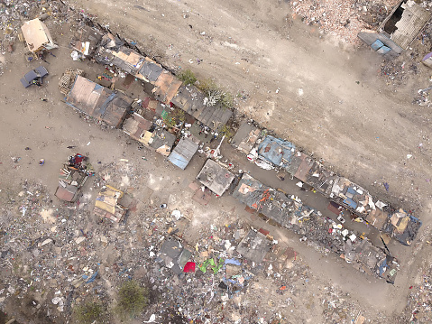 Aerial top-down view high altitude of slum a heavily populated urban informal settlement characterized by substandard housing and squalor poor living conditions streets and rusty metal home roof tops
