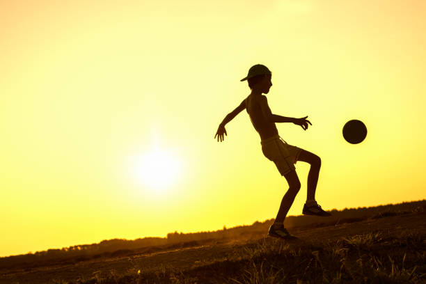 istock Boy playing with ball in nature in hot evening 1219596841