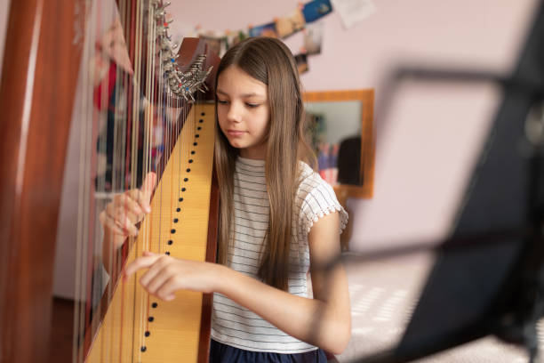 mädchen spielt harfe zu hause - harfe stock-fotos und bilder