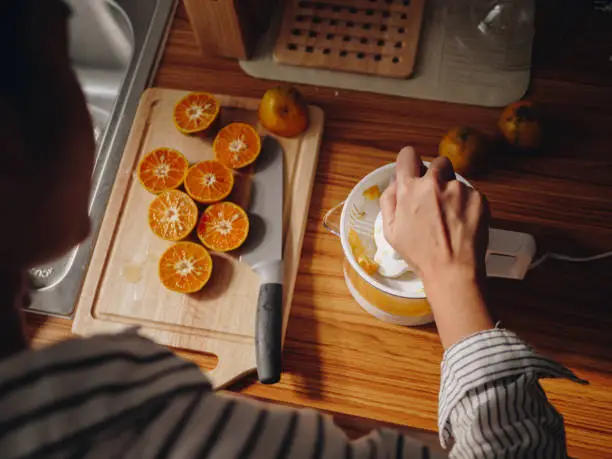 Young asian woman chopping up fruit for her juice in morning at home.