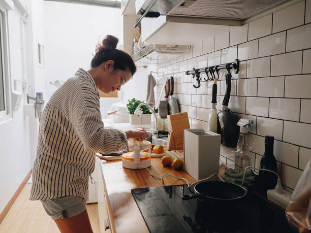 istock Young woman preparing squeezing orange juice at home. 1219598280