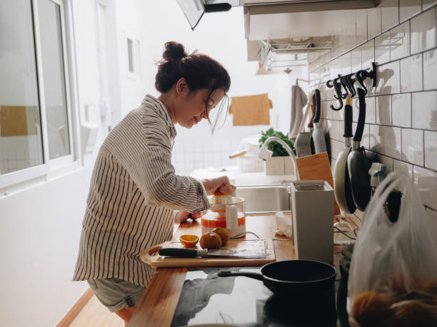 istock Young woman squeezing orange with juicer machine at the kitchen counter 1219598291