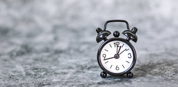 istock Black vintage alarm clock on a grey retro background 1219600714