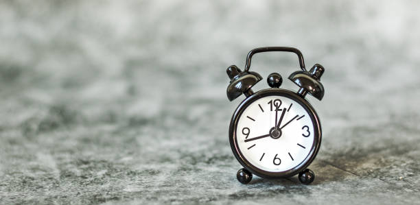 istock Black vintage alarm clock on a grey retro background 1219600724