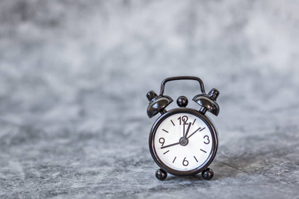 istock Black vintage alarm clock on a grey retro background 1219600883