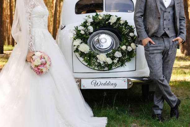 stilvolle hochzeitspaar, elegante brautpaare, bräutigam und braut posiert in der nähe weiß just married auto mit derinschrift ''hochzeit'' - veil bride lace married stock-fotos und bilder