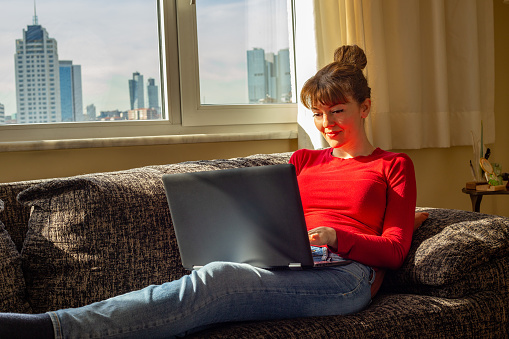 Young Lady in Red working with her laptop by the window