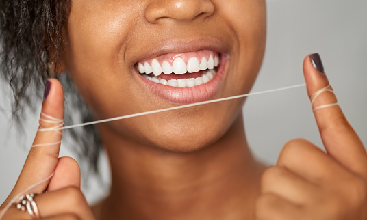 Close-up shot of a young woman showing dental floss