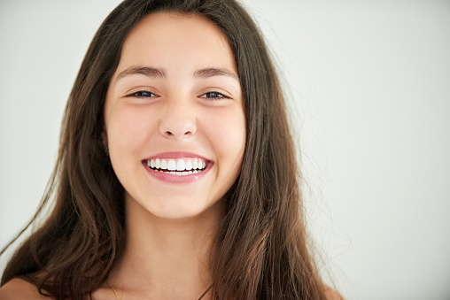 Close-up portrait of a attractive girl with a beautiful toothy smile against white background