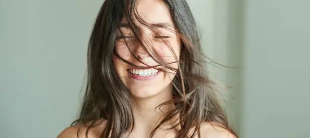 Close-up portrait of a beautiful girl smiling with her hair blowing in wind