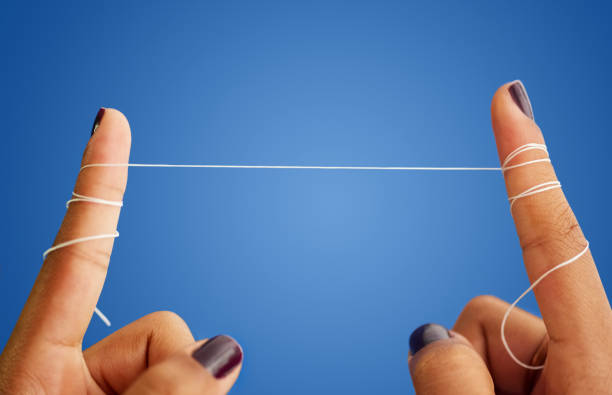 Flossing is important for dental hygiene Close-up shot of a woman fingers holding dental floss against blue background tooth in hand stock pictures, royalty-free photos & images