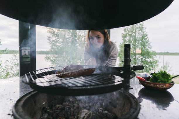istock Woman grilling steak on fire 1219614585