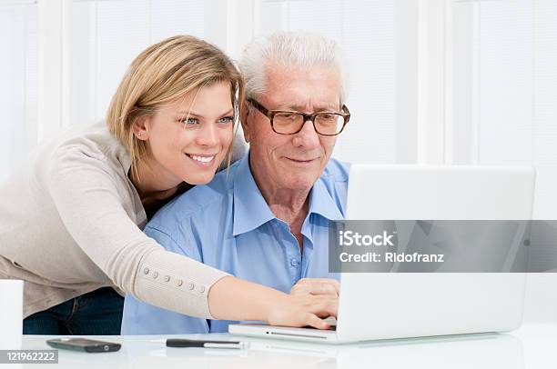 Young Woman Helping Older Man On Laptop Stock Photo - Download Image Now - Senior Men, Young Women, Computer