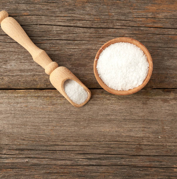 istock white coarse salt in a wooden spoon, gray table from old boards 1219624839