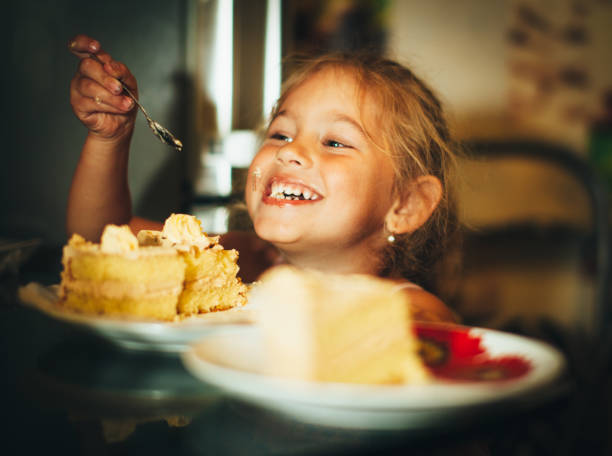 happy little girl eating cake - little cakes imagens e fotografias de stock