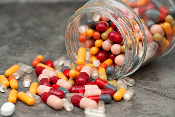Pills spilling out of a jar. Medicine spilling out of a pill container. Health supplement. antibiotic stock pictures, royalty-free photos & images