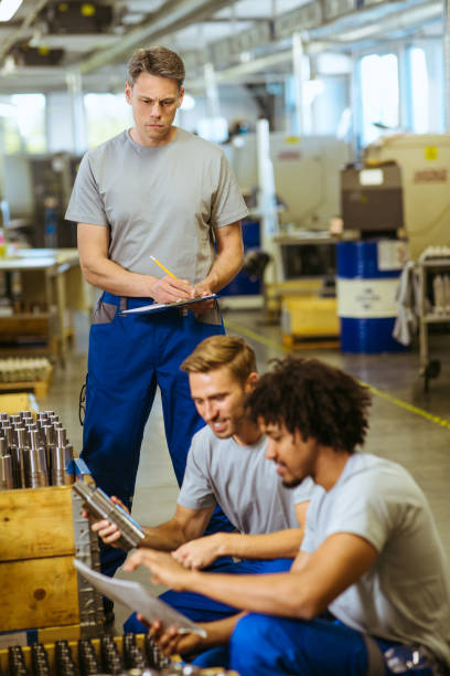 istock Senior male inspector doing quality control with manual worker looking at document 1219630526