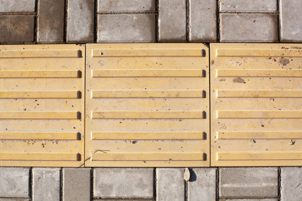Bright yellow tactile paving for the visually impaired on the sidewalk.
