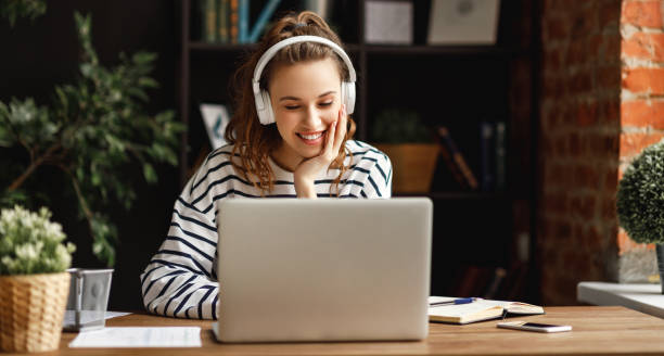 istock Excited woman in headphones having conversation on video chat while using laptop at home 1219638443