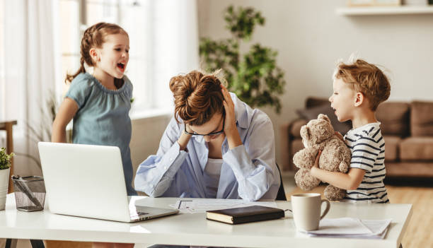 自宅でラップトップ上の仕事から忙しい若い女性をそらす小さないたずらな子供たち - home  audio ストックフォトと画像