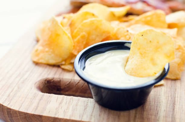 istock Potato chips and dip on wooden board 1219641339