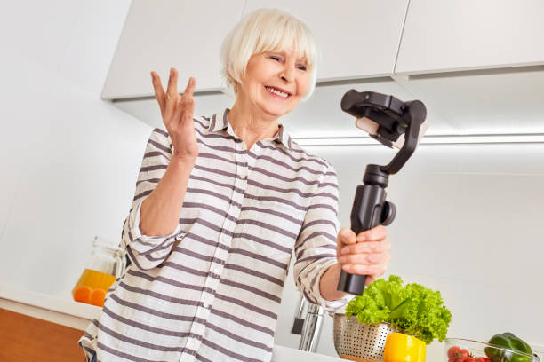 seniorin mit modernem smartphone, in der küche zu hause stehend - smart casual occupation casual healthy eating stock-fotos und bilder