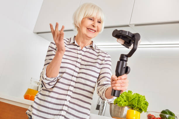 istock Senior woman using modern smartphone, standing in kitchen at home 1219641807