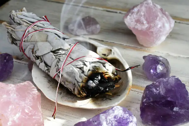 A close up image of a burning white sage smudge stick used for energy clearing and healing.
