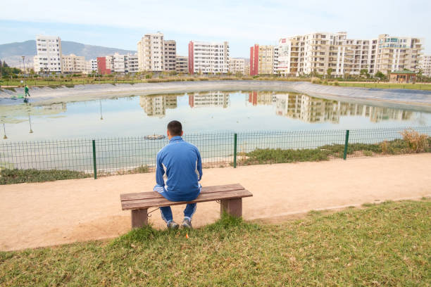 Fez, Morocco - February 10, 2016: A local man sits at a bench in front of the pond at Parc Champ de Course in Fez’ New Town.