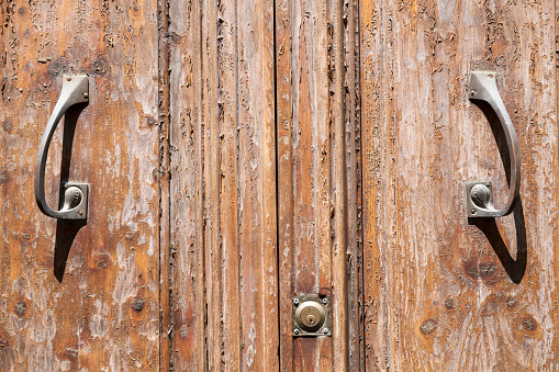 Old iron ring black knocker on vintage wooden retro brown door for knocking on facade classical europe house