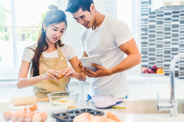 istock Asian couples cooking and baking cake together in kitchen room. 1219653300