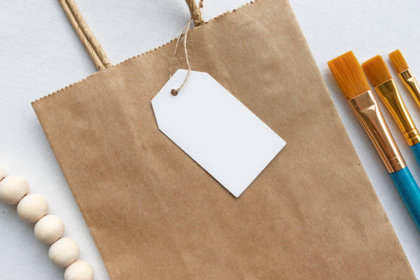 istock Blank white gift luggage tag on a brown paper bag 1219661723