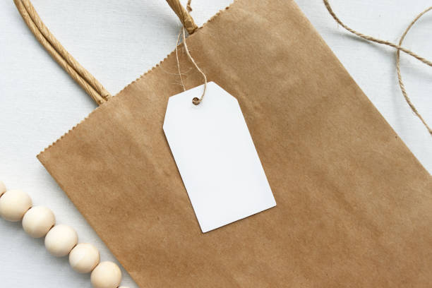 Blank white gift luggage tag on a brown paper bag