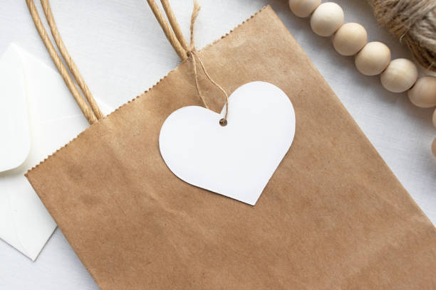 Heart shaped gift tag label on a brown paper bag - flat lay gift tag mockup