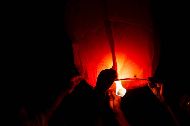 istock Person holding a red sky lantern with the flames showing clearly 1219663423