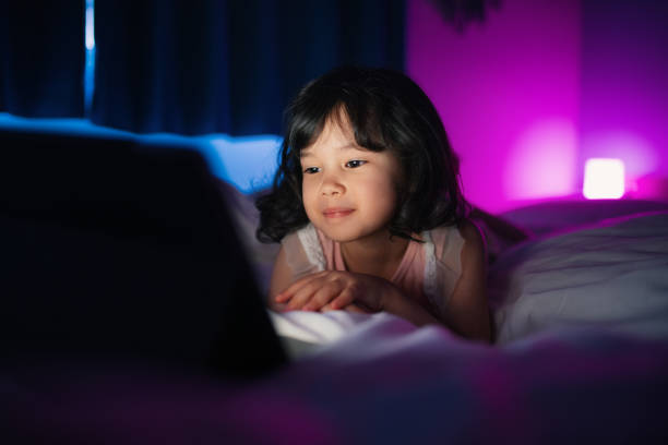 istock Young girl watching at a digital tablet at home at night 1219670537