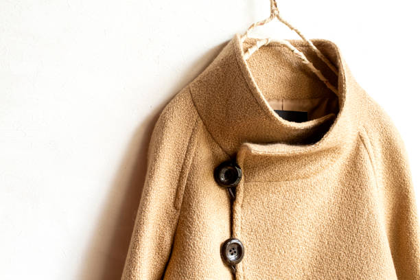 istock beige wool coat hanging on clothes hanger on white background. 1219680237