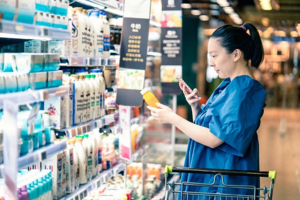 donna incinta asiatica che fa la spesa al supermercato e sceglie la salsa in bottiglia - human pregnancy clothing shopping retail foto e immagini stock
