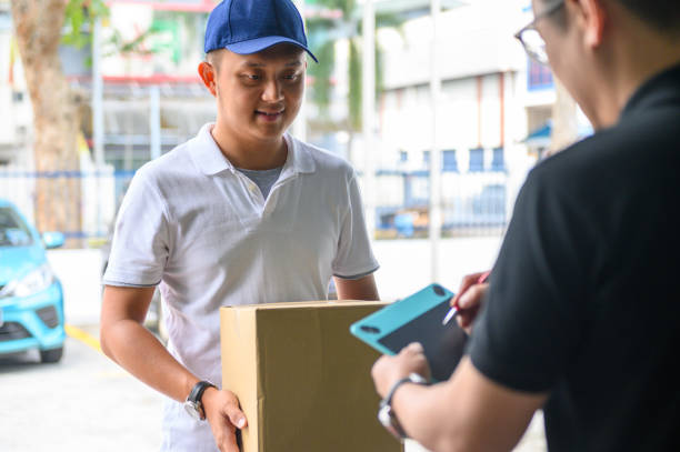 istock Man accepting a delivery of box from deliveryman with digital device 1219682620