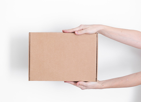 A parcel cardboard box in a delivery man hands on a white background. Delivery service concept.
