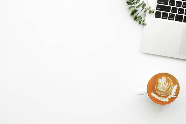 istock White minimalist office desk table with laptop computer and cup of latte coffee. Top view with copy space, flat lay, minimal style. 1219688792