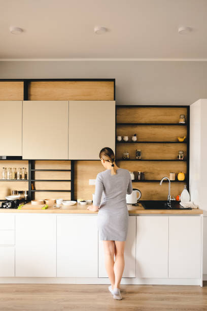 istock Back view of woman standing next to a modern kitchen 1219691236