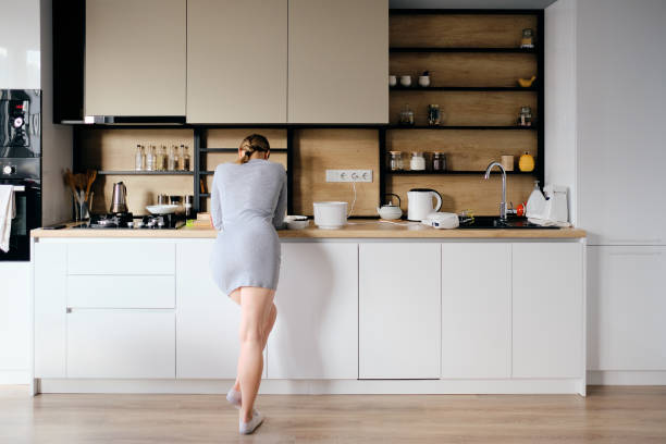istock Back view of woman standing next to a modern kitchen 1219691253