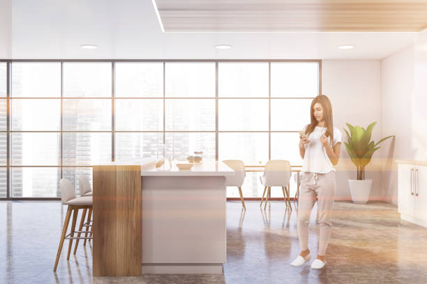 istock Woman in panoramic white kitchen with bar 1219691784