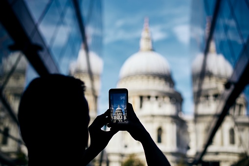 Man photographing with smart phone. Tourist taking picture of St. Paul's Cathedral in London, United Kingdom.