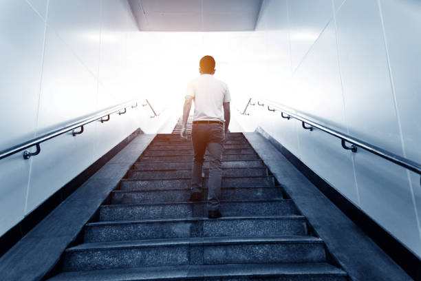 istock Rear view of man climbing the staircases 1219695986